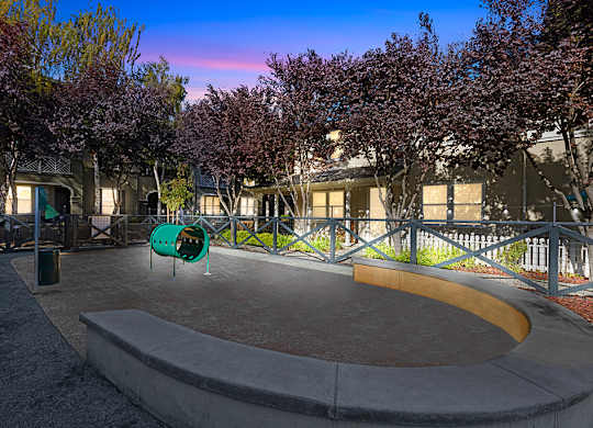 A playground with a slide and a purple tree.