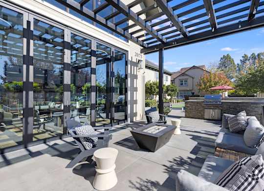 A modern outdoor patio with a glass wall and a stone fireplace.