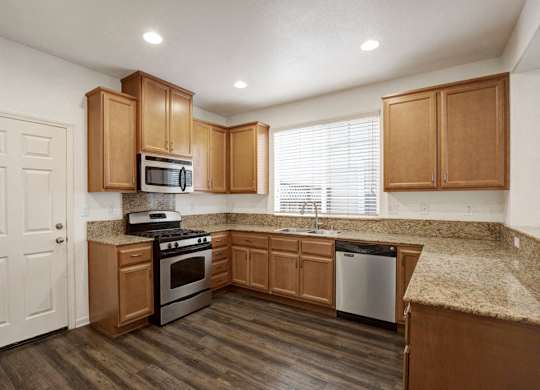 A kitchen with wooden cabinets and a granite countertop.