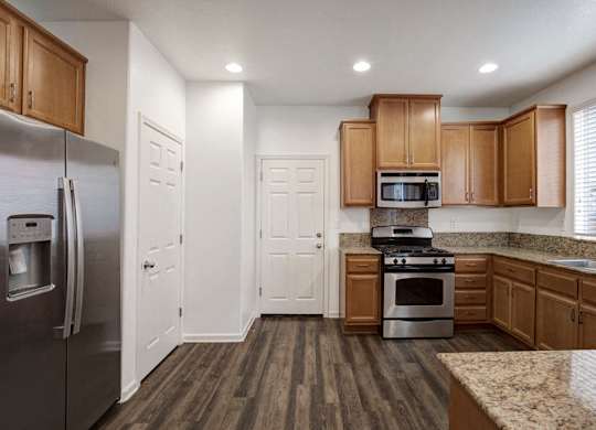 A kitchen with wooden cabinets and a granite countertop.