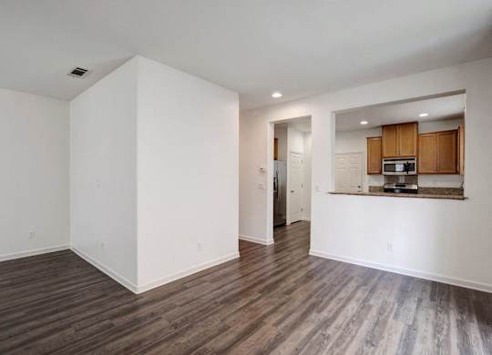 A spacious room with wooden flooring and white walls.