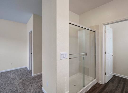 A room with a glass shower stall and a white door.