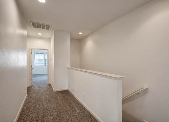 A long hallway with a carpeted floor and white walls.