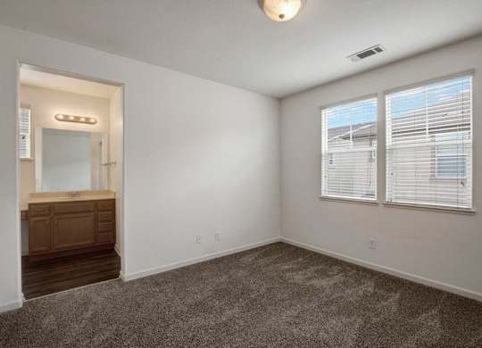 A room with a carpeted floor and a window with blinds.