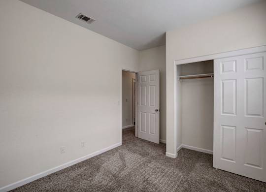 A room with a carpeted floor and two white doors.