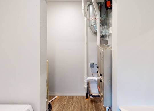 A white wall with a pipe and a white chair.