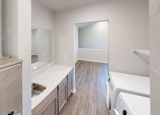 A kitchen with white appliances and wooden floors.