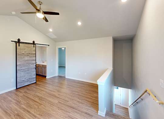 A room with a ceiling fan and wooden flooring.