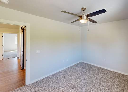 A room with a ceiling fan and carpeted floor.
