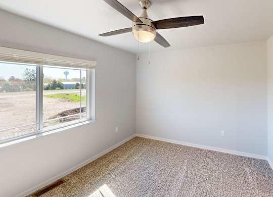 A room with a ceiling fan and a carpeted floor.