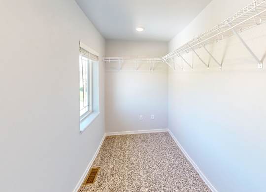 A room with white walls and a window on the left side.