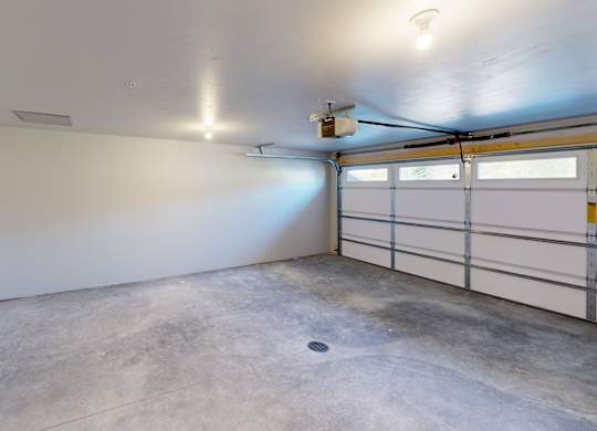 A spacious garage with a concrete floor and a white wall.