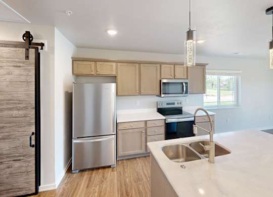 A kitchen with a sink, refrigerator, and microwave.