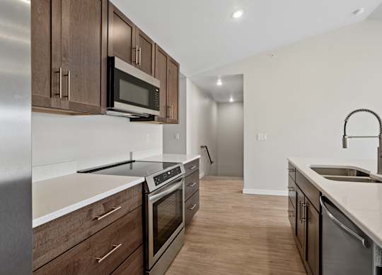 A modern kitchen with dark wood cabinets and stainless steel appliances.