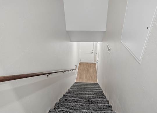 A stairway with a wooden floor and a metal handrail.