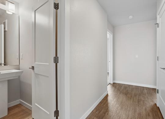 A white bathroom with a wooden floor and a white door.