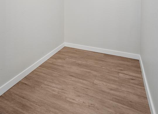 A white wall with a wooden floor and a white ceiling.