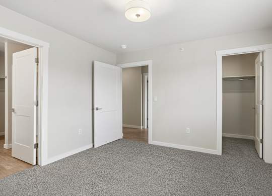 A room with white walls and a grey carpet.