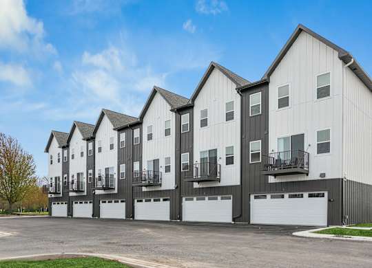 A row of modern townhouses with garages in front.
