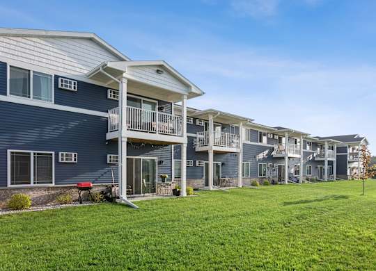 A row of houses with balconies and a green lawn in front.