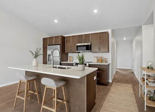 A kitchen with a white countertop and wooden bar stools.