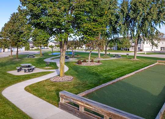 A green lawn with a small putting green and a wooden fence.