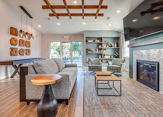 A modern living room with a grey couch, a wooden coffee table, and a fireplace.