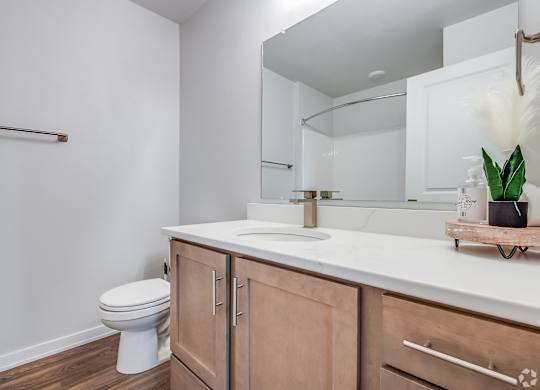 A white toilet sits in a bathroom with wooden cabinets.