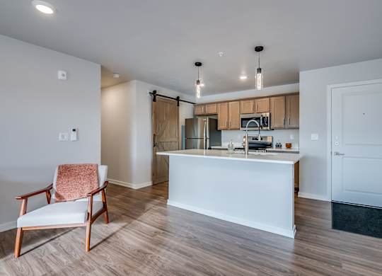 A kitchen with a white island and a chair with a pink towel on it.