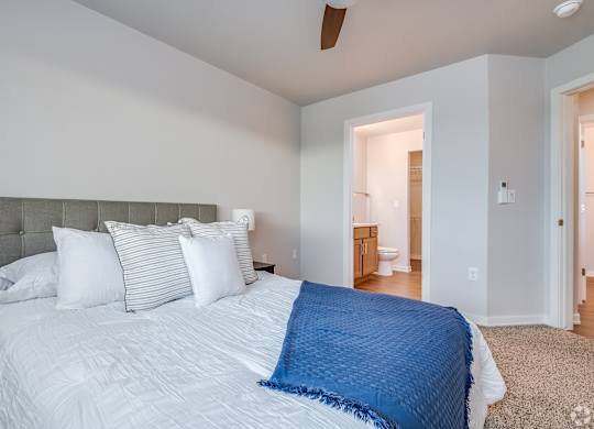 A bedroom with a large bed and a ceiling fan.