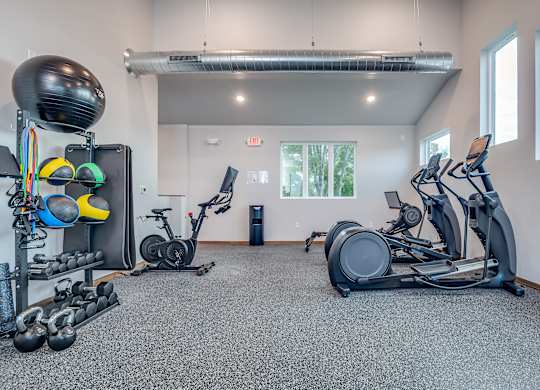 A gym with a variety of equipment including a stationary bike, a rowing machine, and a weight rack.