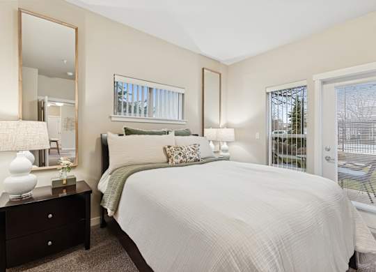 A bedroom with a large bed, a dresser with a mirror, and a window with blinds.