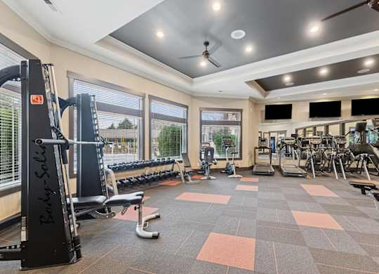A gym with a variety of equipment including a weight bench, treadmill, and exercise machines.