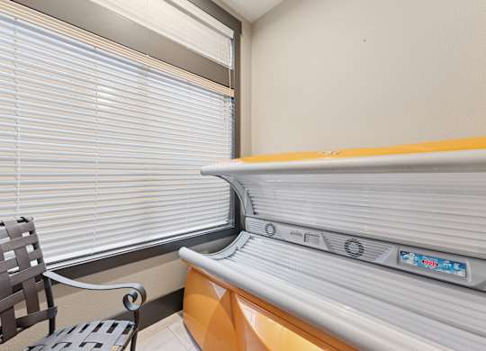 A room with a window covered by blinds and a bench with a backrest.