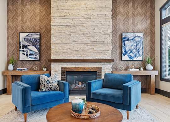 A living room with a fireplace and two blue chairs.