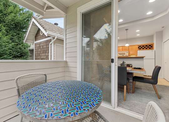 A table with a blue and green patterned top is on a porch.