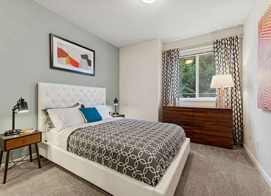 A bedroom with a large bed and a window with curtains.