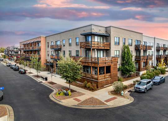 Apartment complex with a parking lot in front.