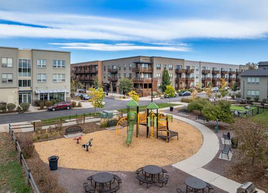 A playground with a green slide and a yellow slide in the middle of a park.