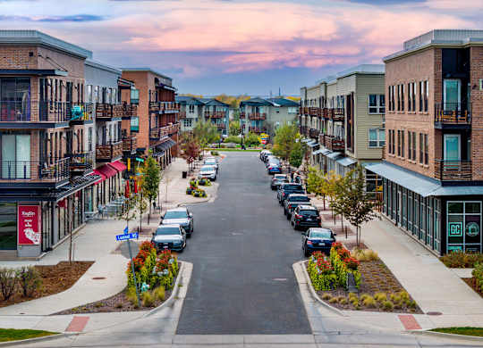 A street view of a residential area with cars parked on the side of the road.