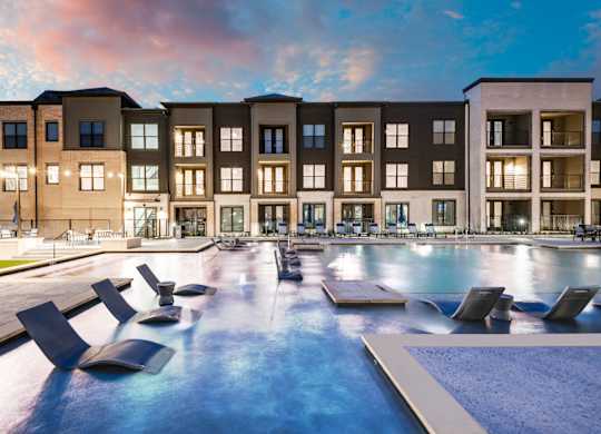 A modern apartment complex with a pool in front.