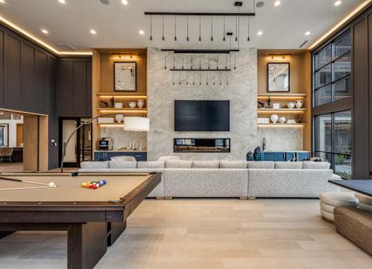 A modern living room with a pool table and a fireplace.