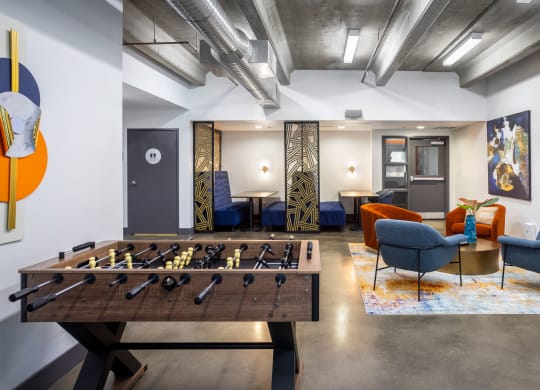 a living room with a foosball table and a game room with couches