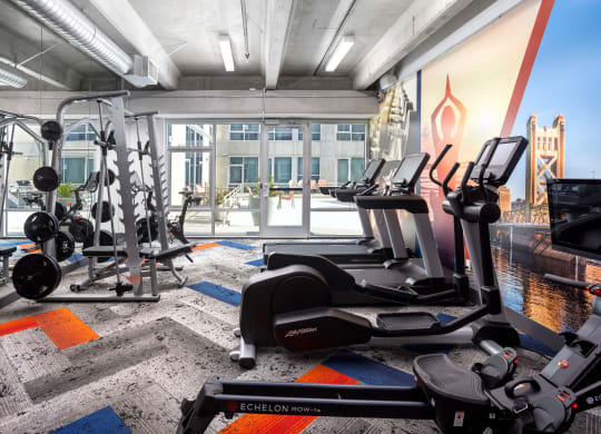 a gym with weights and cardio equipment in a room with a large window