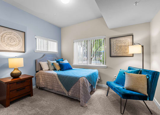 a bedroom with a bed and a chair and a window