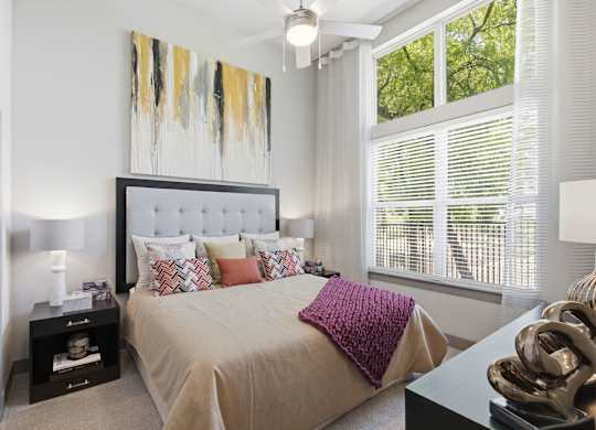 A bedroom with a large bed and a painting above it.