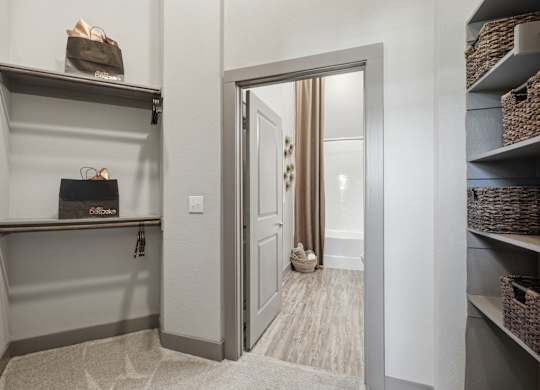 A hallway with a shoe rack and a doorway leading to a room.