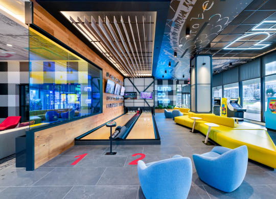 a bowling alley in the lobby of a building with blue and yellow couches