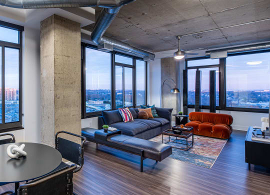 a living room with a couch and a table in a room with large windows