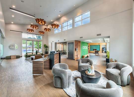 A modern office lobby with grey armchairs and a wooden floor.